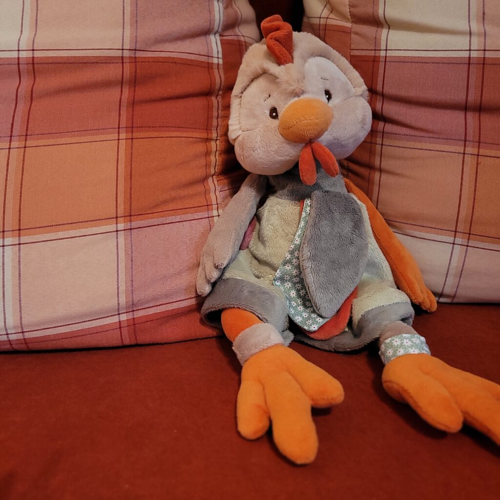 Eine oranges Plüschhuhn auf dem Sofa