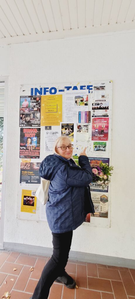 vor der Lesung in Wolfsburg steht Silke an einer Werbewand